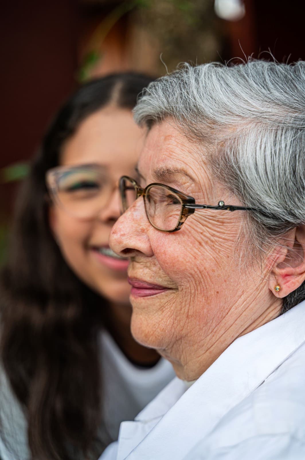 An older person and a younger carer smiling together at home